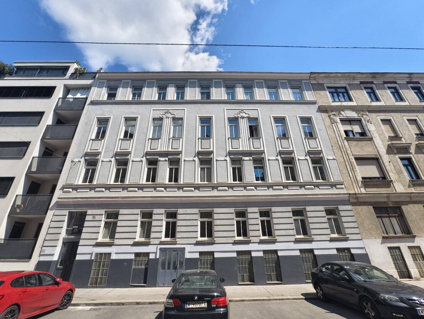 Klassische Fassade eines Mehrfamilienhauses mit vielen Fenstern und Balkonen.