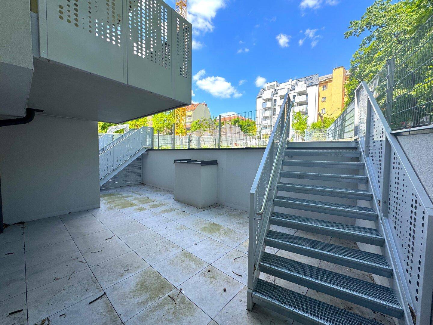 Gepflasterte Außenterrasse mit modernen Metalltreppen, die zu den oberen Ebenen führen.