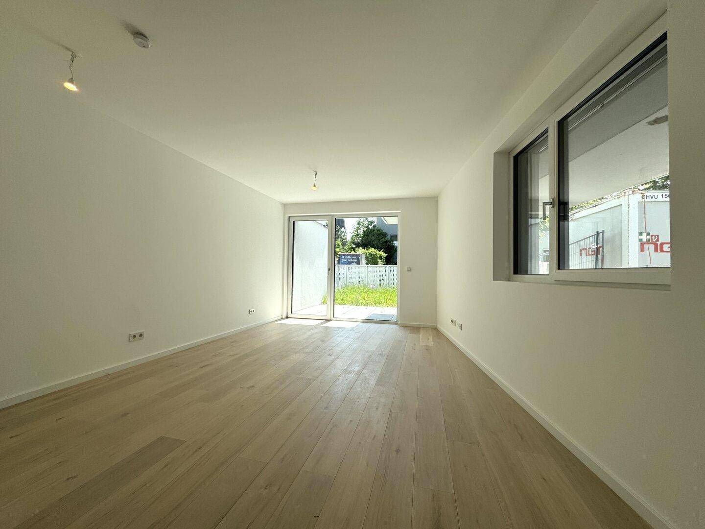 Geräumiger, heller Raum mit Holzboden und großer Schiebetür, die den Zugang zum Garten ermöglicht.