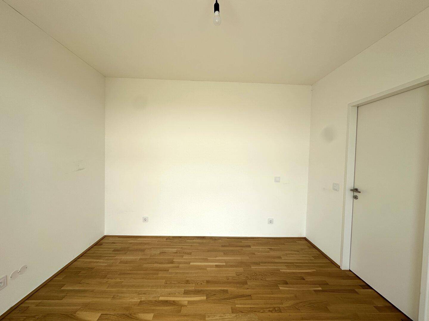 Geräumiges Schlafzimmer mit hellem Parkettboden und weißen Wänden, bereit zur individuellen Gestaltung.