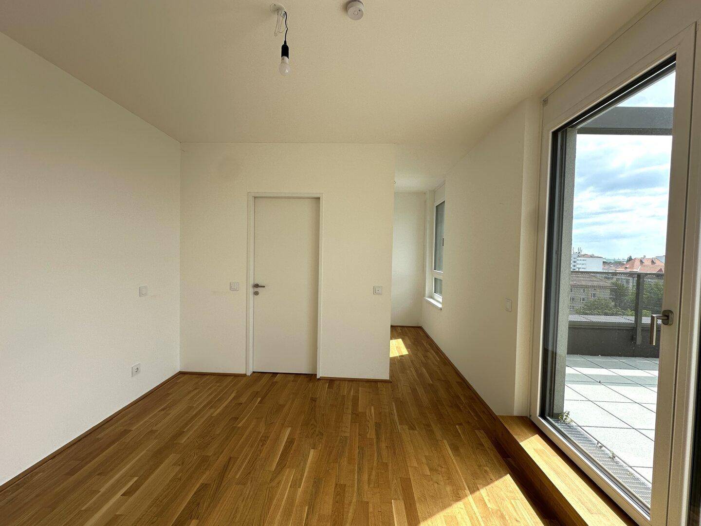 Helles Schlafzimmer mit Parkettboden, großen Fenstern und direktem Zugang zur Terrasse.