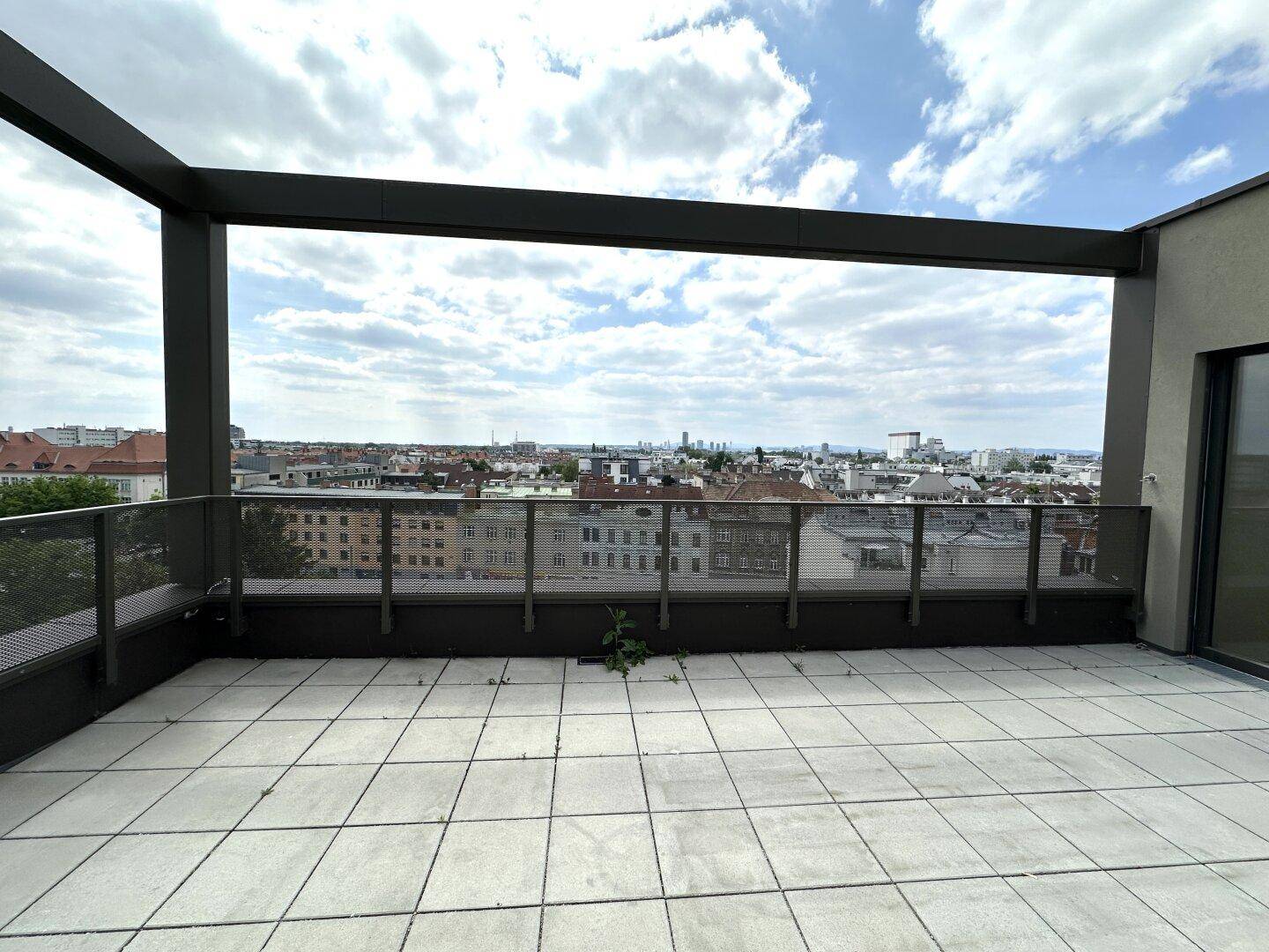 Große Dachterrasse mit Stadtblick, Fliesenboden und moderner Metallbrüstung.