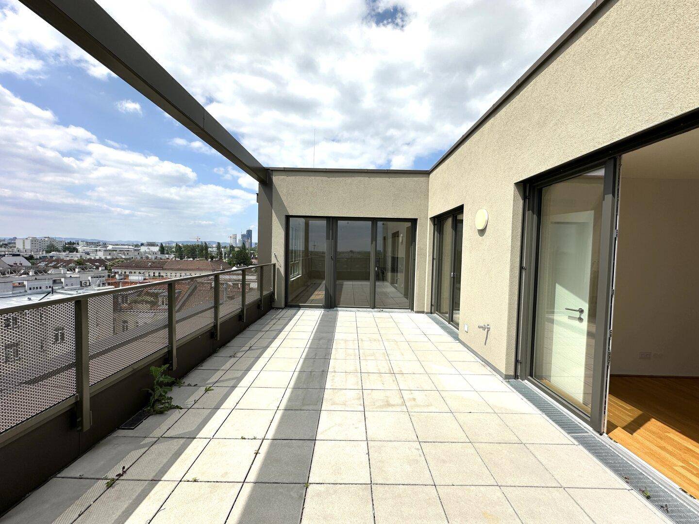 Weitläufige Dachterrasse mit Zugang zu den Innenräumen und Panoramablick über die Stadt.
