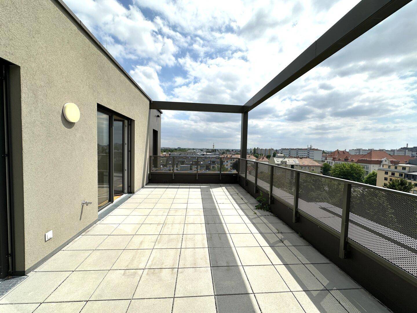 Geräumige Dachterrasse mit moderner Architektur, Fliesenboden und weitem Stadtblick.