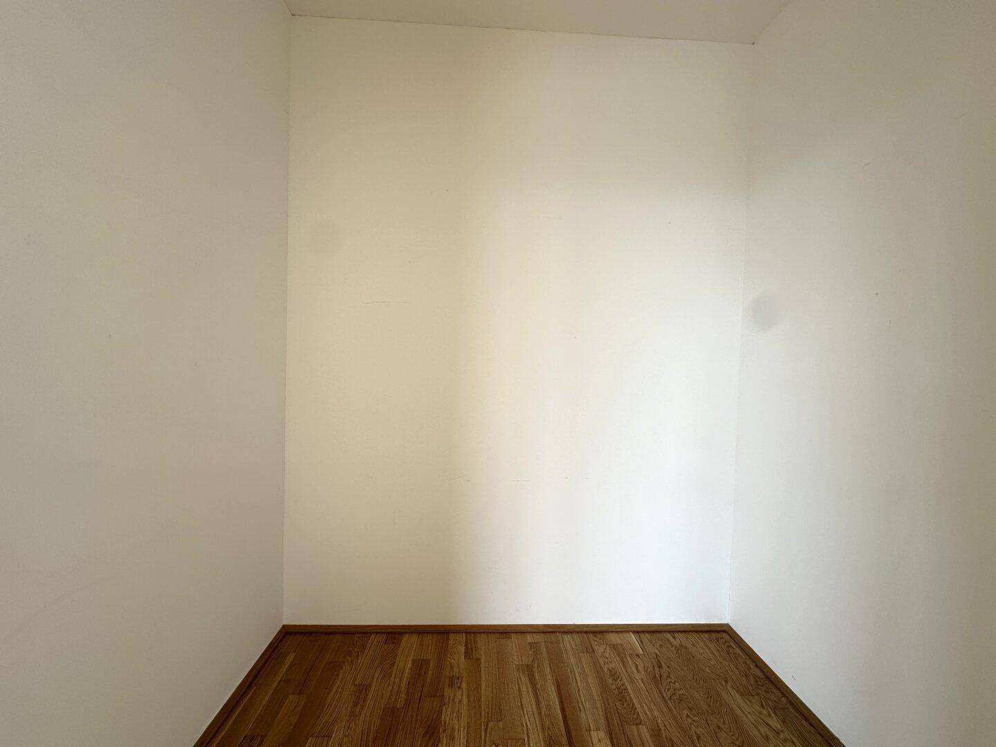 Kleiner, leerer Raum mit Parkettboden und weißen Wänden, nutzbar als Abstellraum.