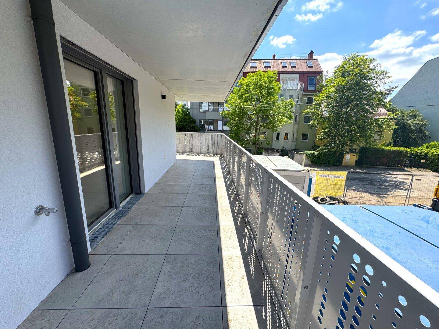 Langer Balkon mit Fliesenboden und modernem Geländer, bietet Zugang zu den Innenräumen.