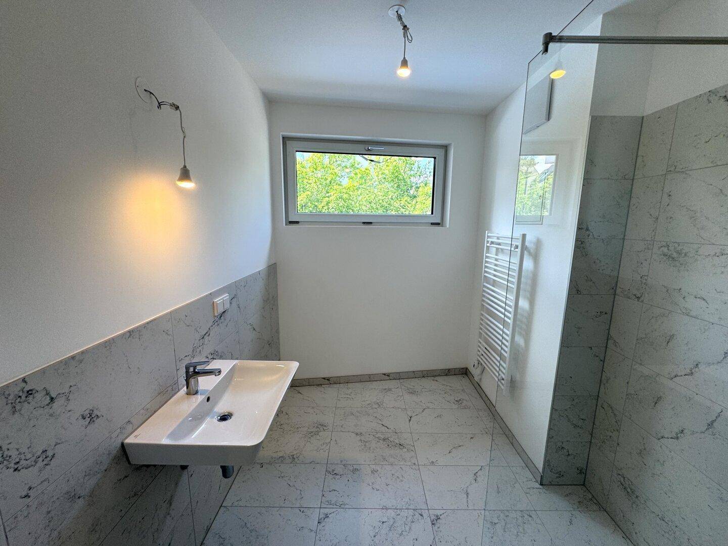 Helles Badezimmer mit Fenster, modernem Waschbecken und beheiztem Handtuchtrockner.