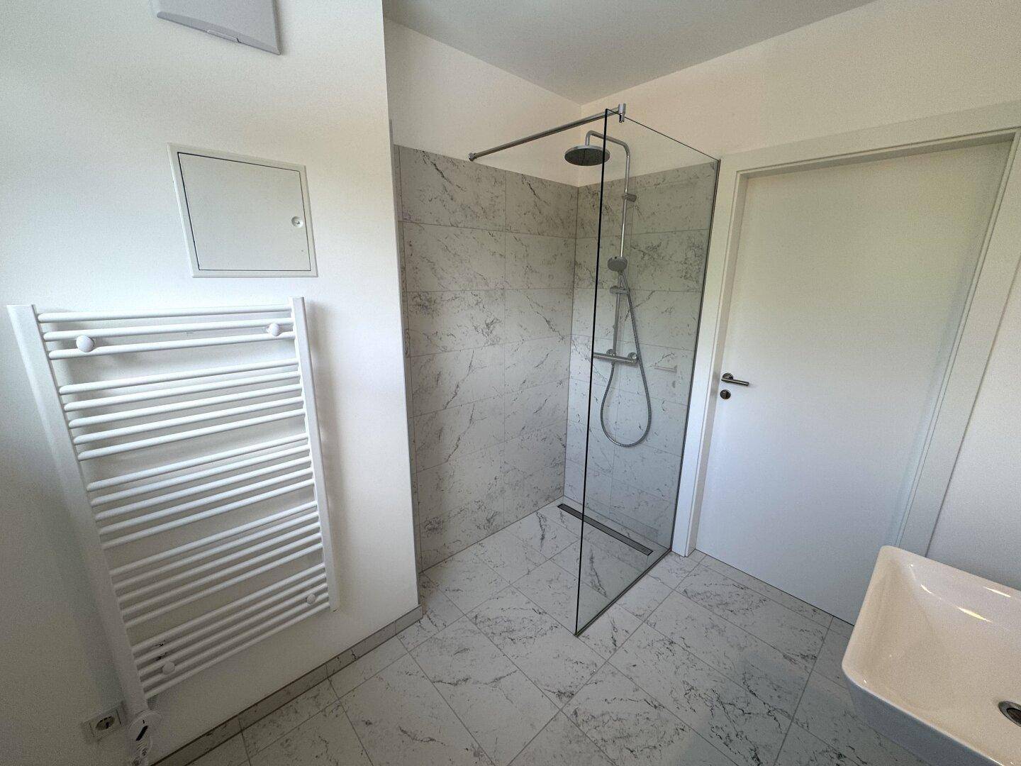 Modernes Badezimmer mit begehbarer Dusche, Marmorfliesen und beheiztem Handtuchhalter.