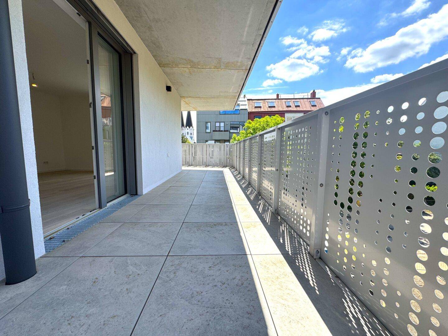 Geräumiger Balkon mit Fliesenboden und moderner Brüstung, direkt zugänglich von einem hellen Innenraum.