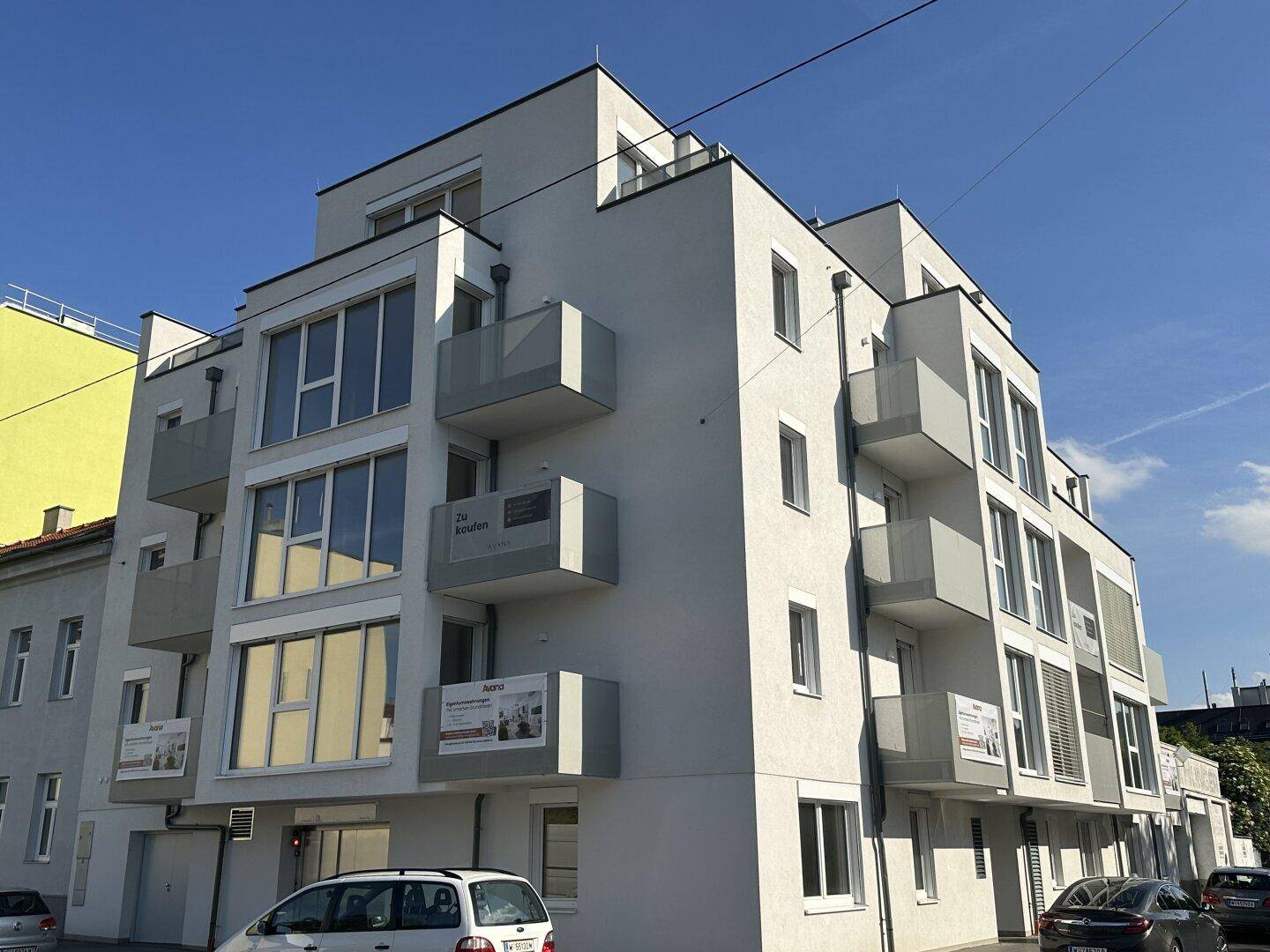 Ansicht des modernen Apartmentgebäudes mit mehreren Balkonen und großen Fenstern von einer anderen Perspektive.