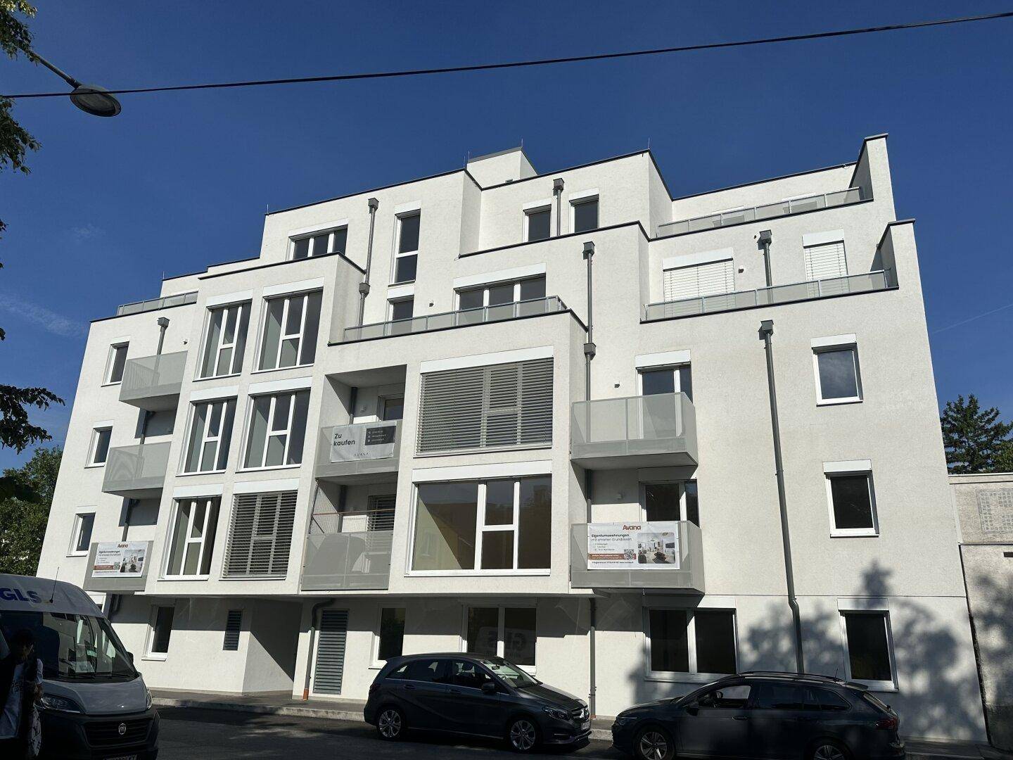 Gesamtansicht des modernen Mehrfamilienhauses mit gestaffelten Balkonen und Flachdach.