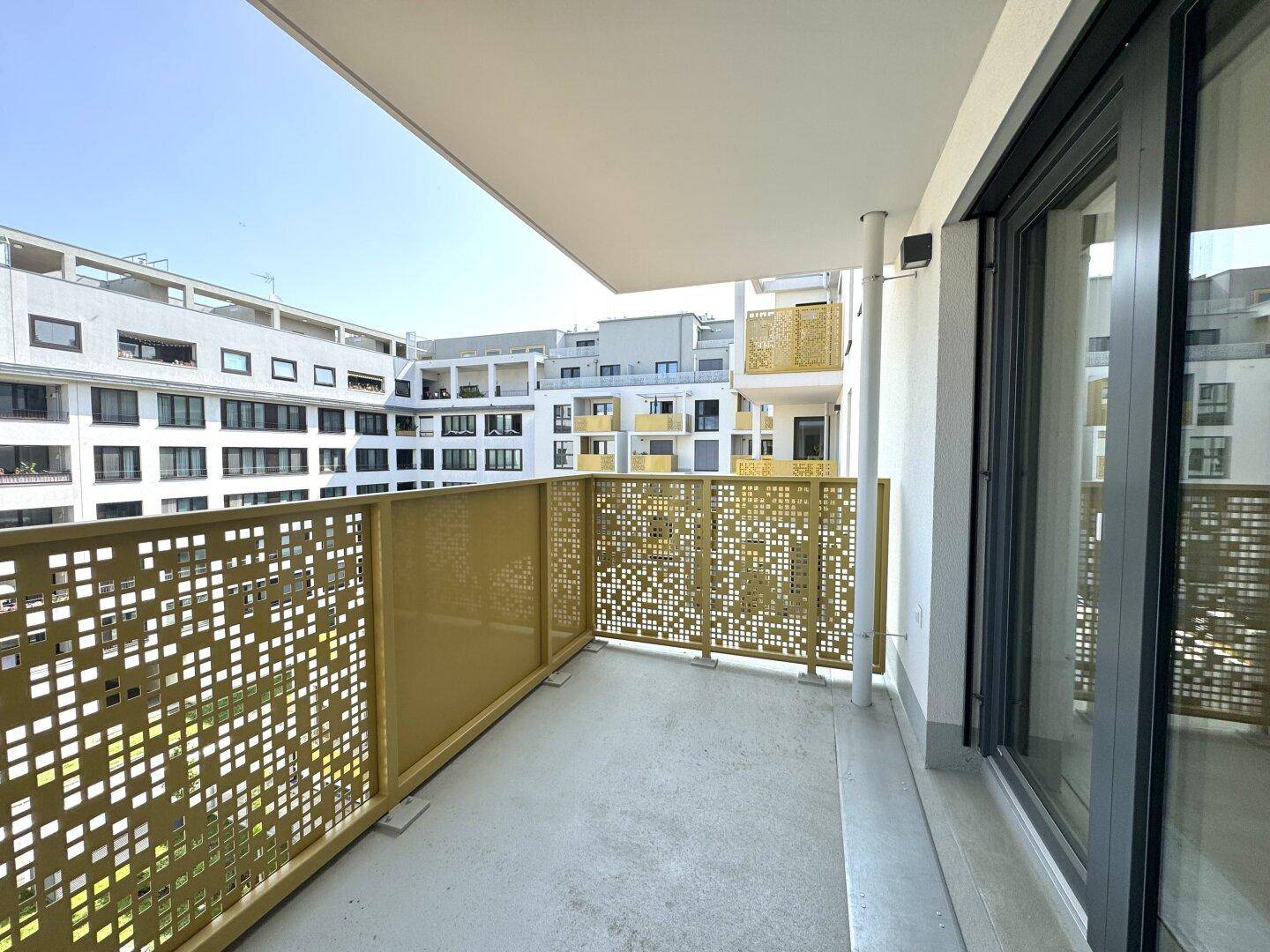 Geräumiger Balkon mit moderner, perforierter Brüstung und Blick auf die umliegenden Gebäude.