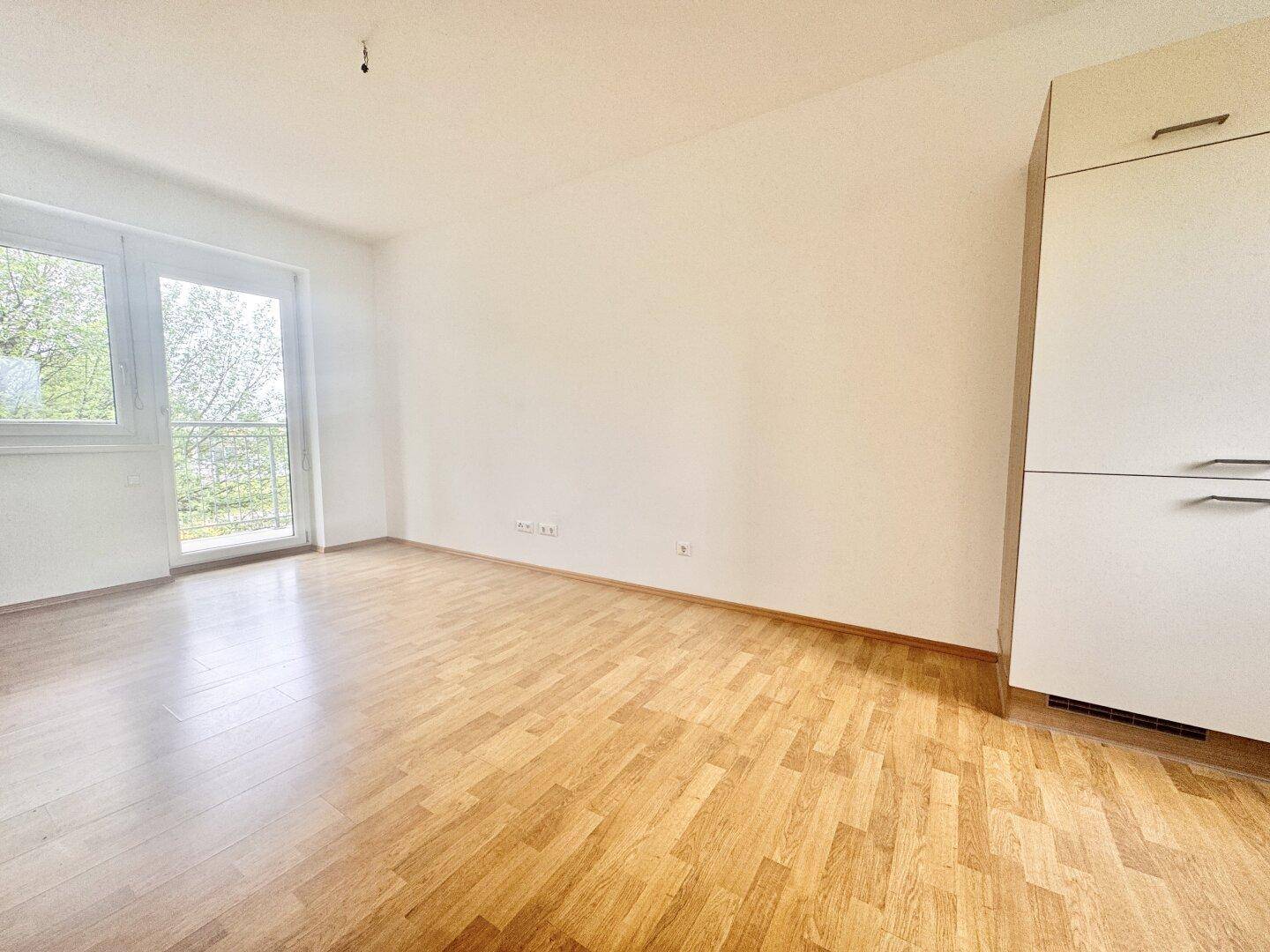 Geräumiges, helles Zimmer mit Parkettboden und Zugang zum Außenbereich.