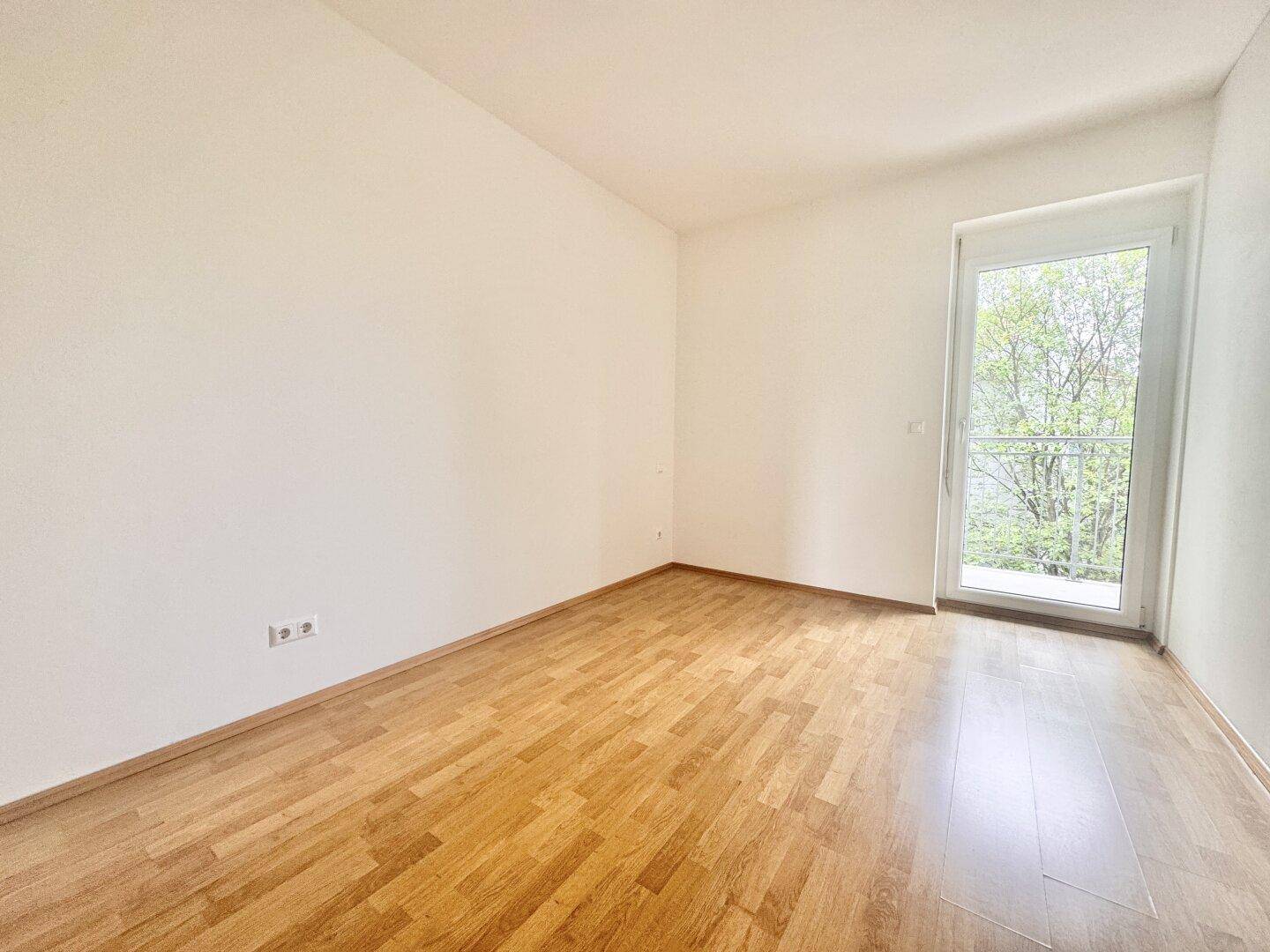 Helles Zimmer mit Parkettboden und großer Balkontür für viel Licht.