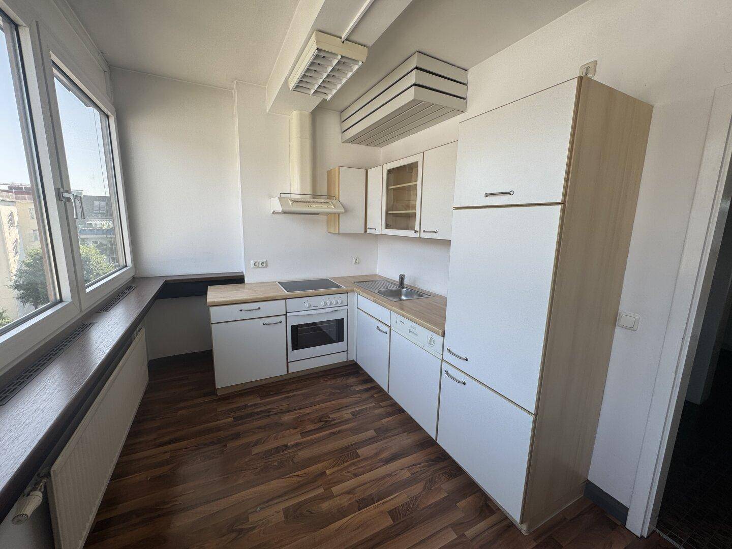 Funktionale Küche mit weißen Schränken, Holztheke und Fenster, bietet ausreichend Arbeitsfläche.