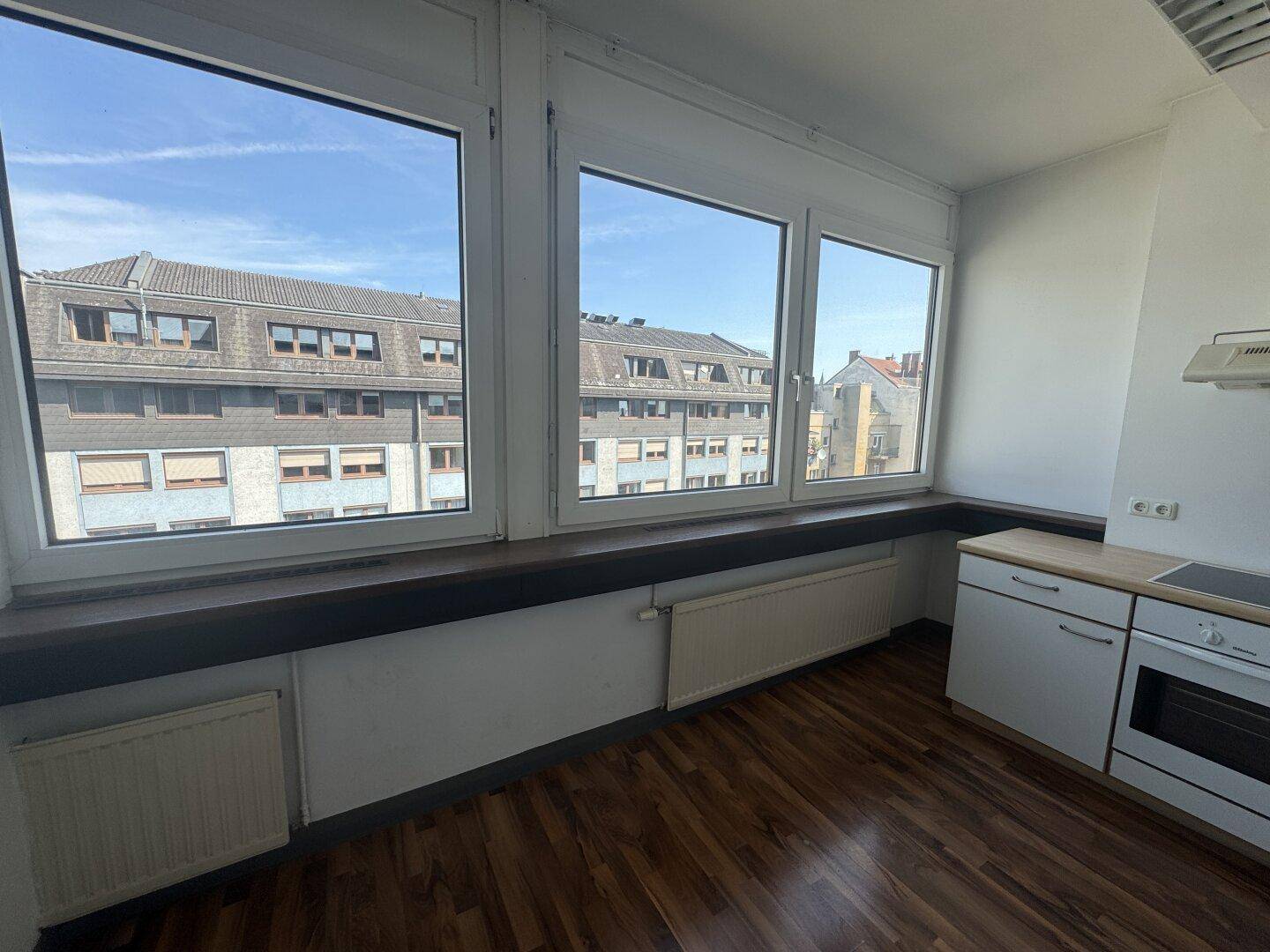 Helle Küche mit Fensterfront, Holzboden und Einbauküche, bietet viel Tageslicht.