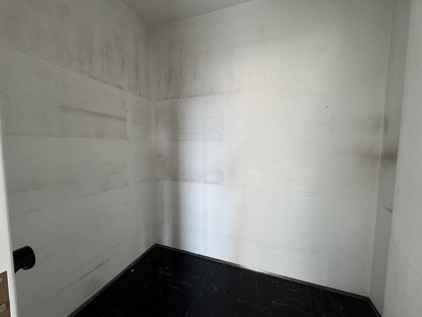 Kleiner Abstellraum mit dunklem Boden und hellen Wänden, ideal für Lagerzwecke.