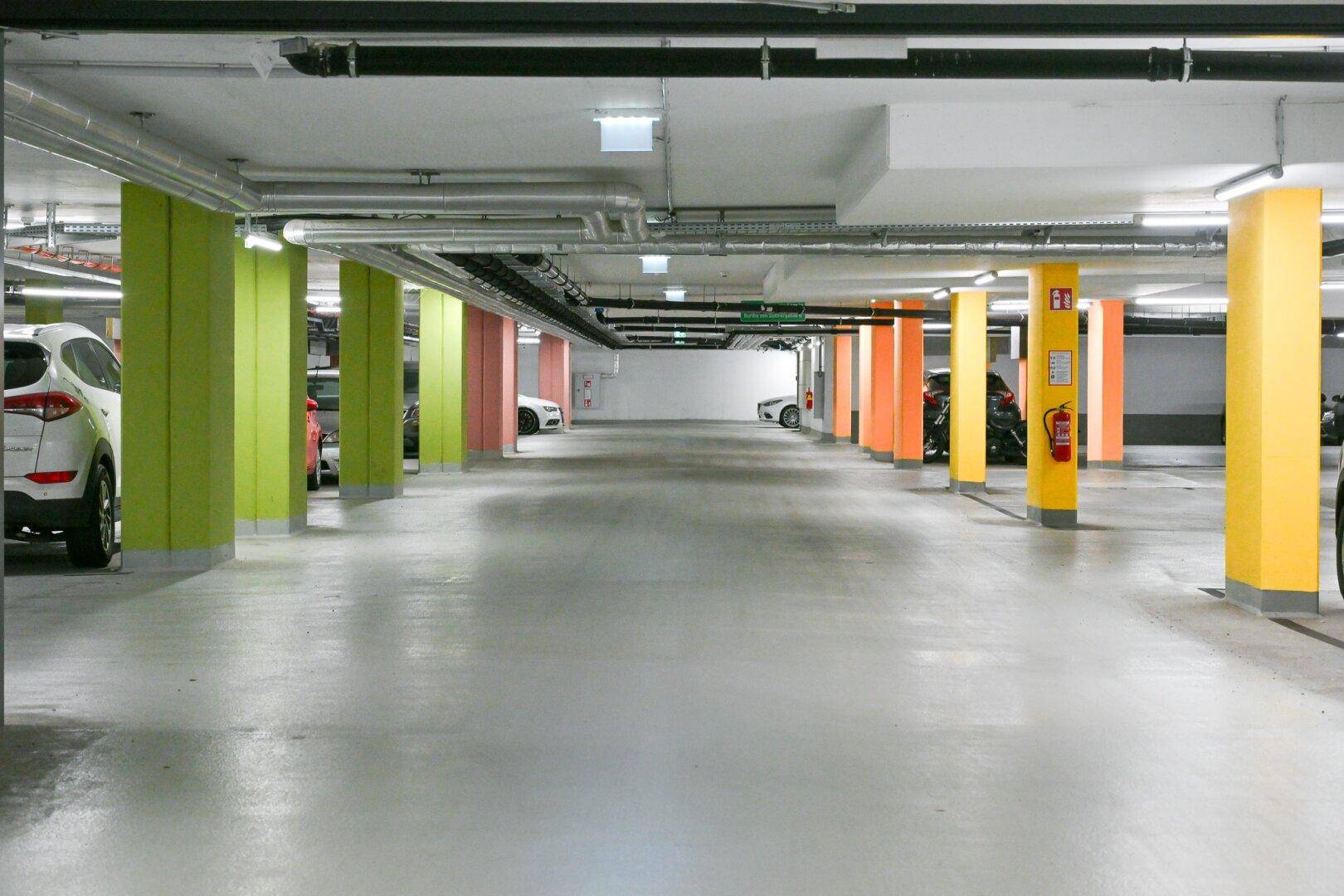 Tiefgarage mit farbigen Säulen und ausreichend Stellplätzen für Fahrzeuge in einem modernen Gebäude.