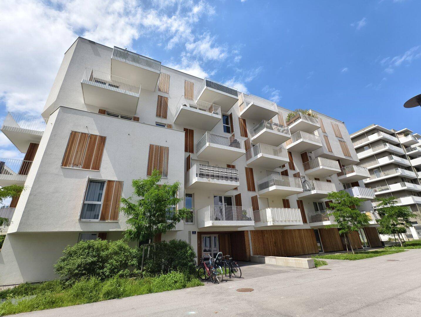 Zeitgenössisches Wohngebäude mit gestaffelten Balkonen und Holzverkleidung an der Fassade.