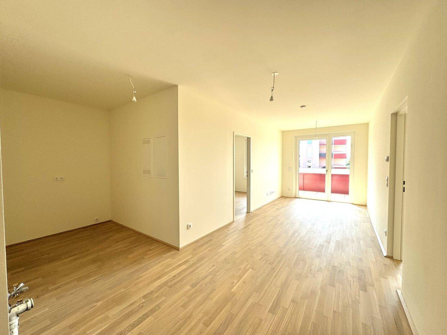 Helles Wohnzimmer mit hellem Parkettboden und direktem Zugang zum Balkon.