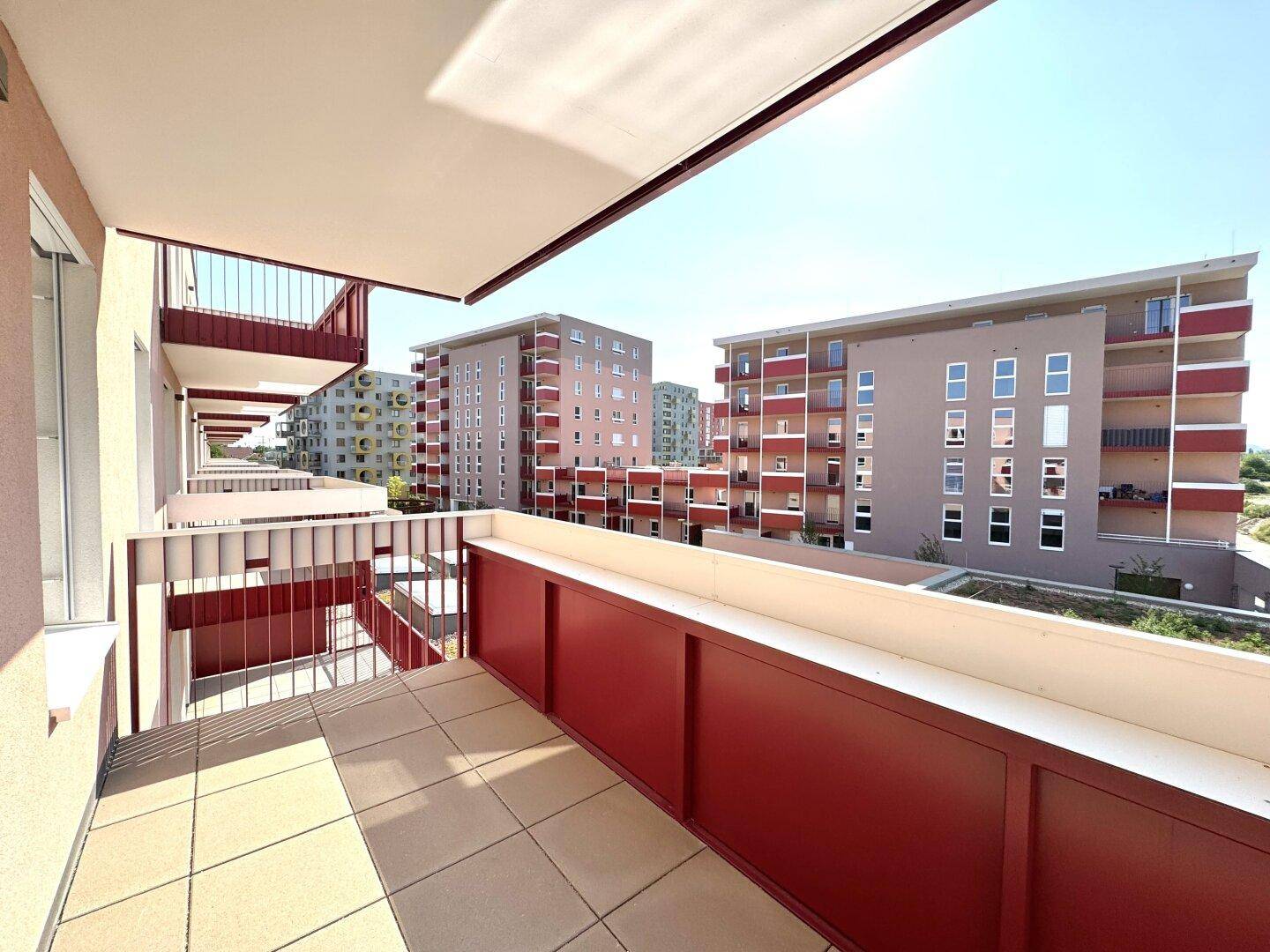 Langer Balkon mit Fliesenboden und Aussicht auf die umliegenden Wohngebäude.