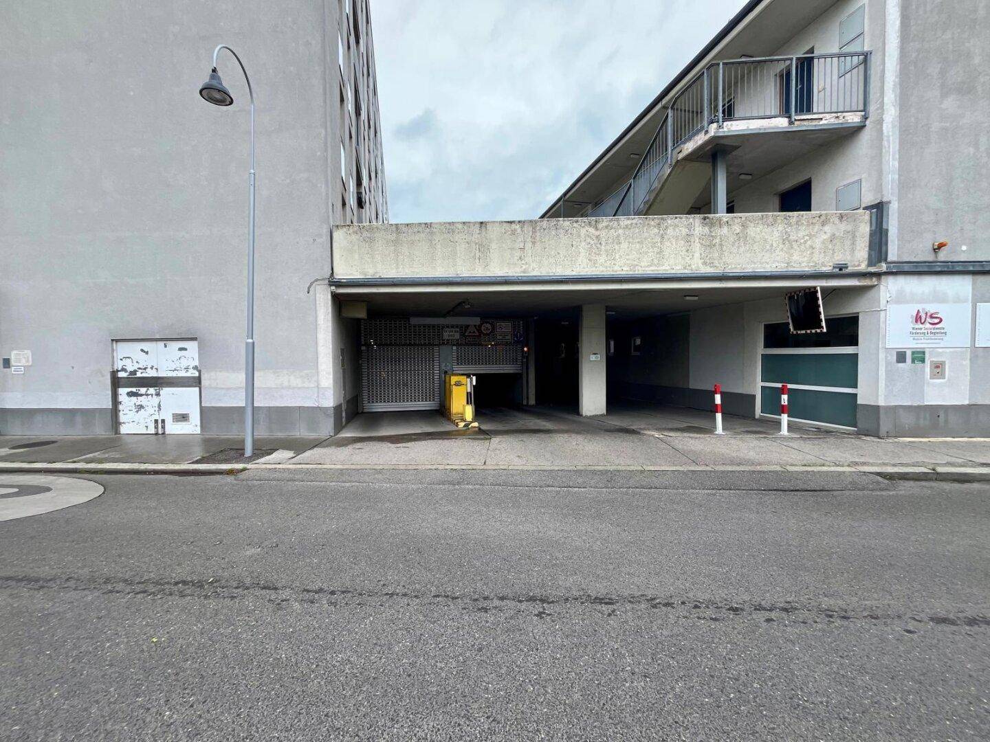 Eingang zur Tiefgarage von der Straße aus, umgeben von modernen Gebäudefassaden.