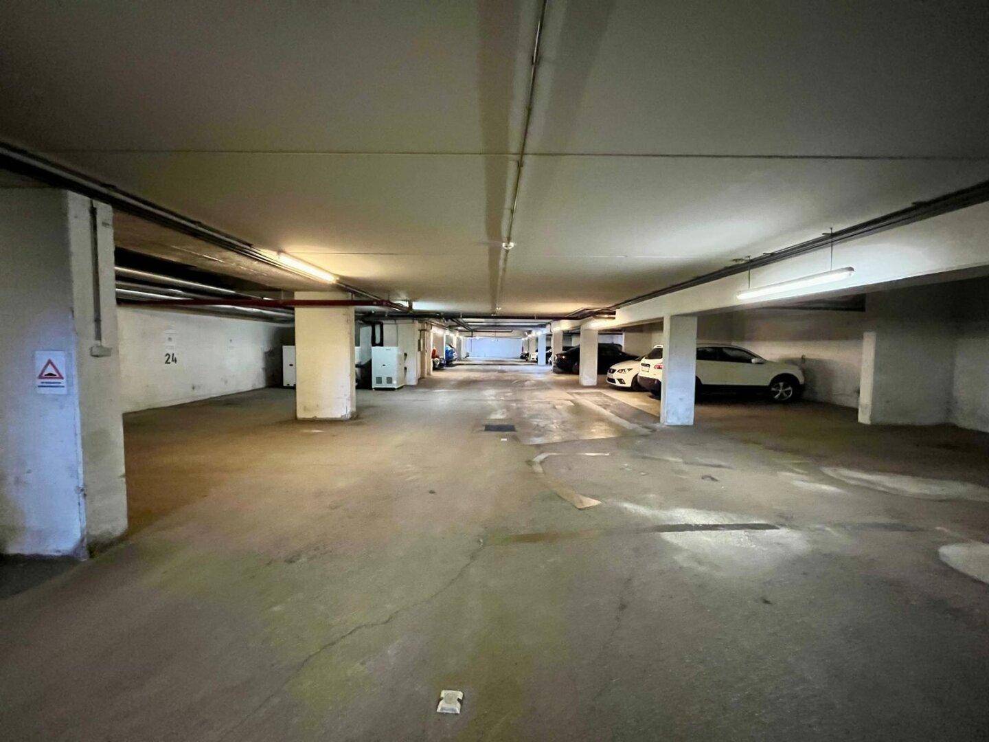 Lange Tiefgarage mit Betonboden und Säulen, bietet ausreichend Parkmöglichkeiten für Bewohner.
