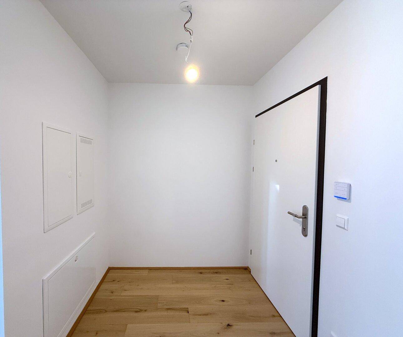 Heller Flur mit Eingangstür und modernen Schaltern, führt zu den weiteren Räumen der Wohnung.