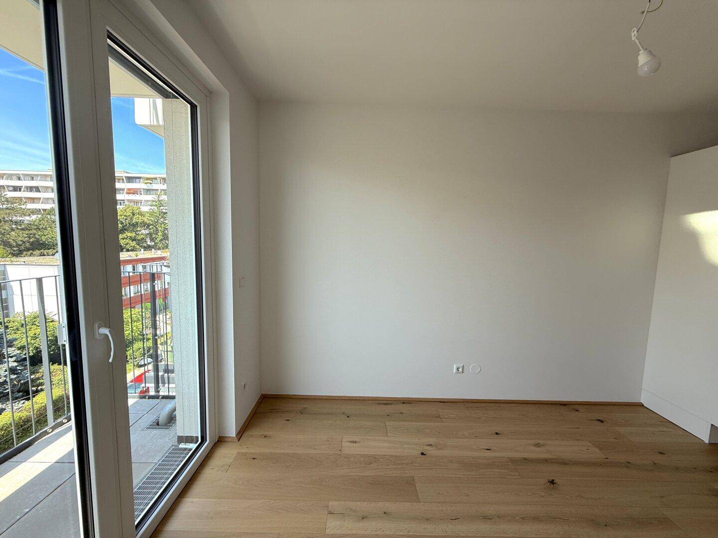 Heller Raum mit großen Fenstern und Zugang zu einem Balkon, bietet viel Tageslicht.