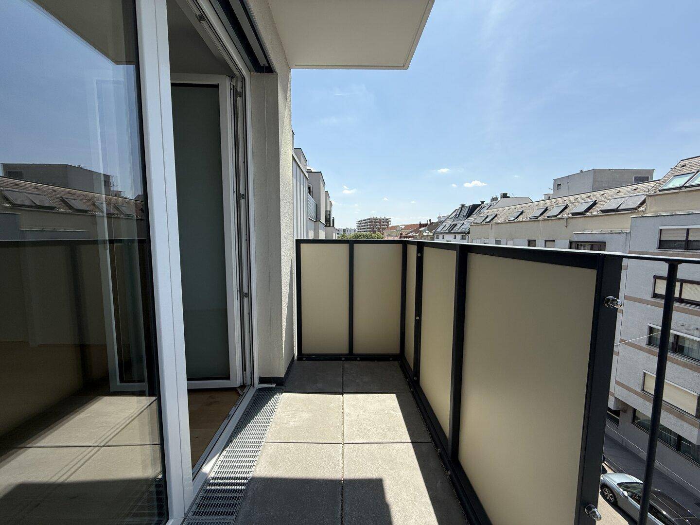 Schmaler Balkon mit Fliesenboden und seitlichem Blick auf die Straße und Nachbargebäude.