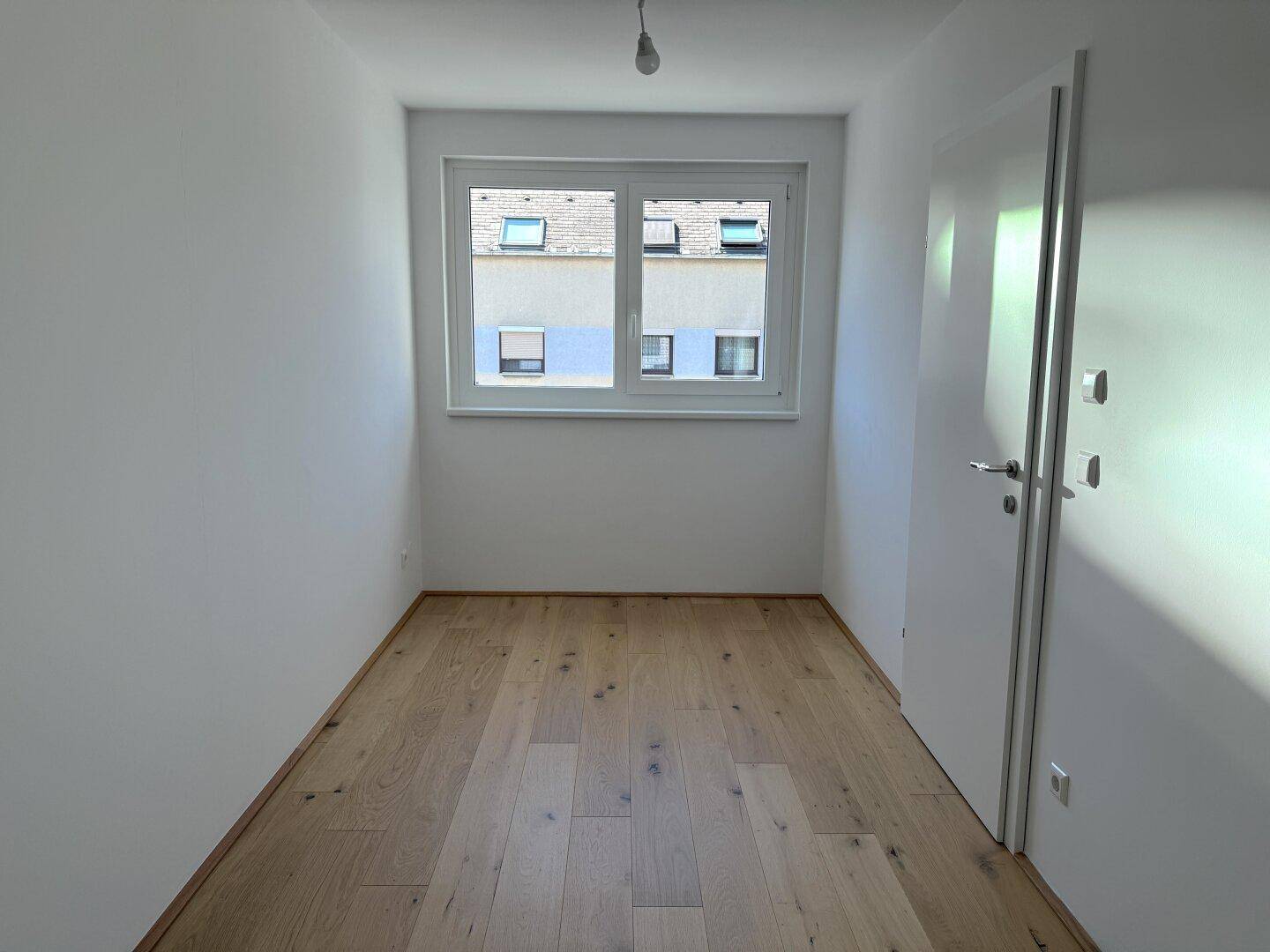 Kleines, helles Zimmer mit Fenster und Parkettboden, geeignet als Schlaf- oder Arbeitszimmer.