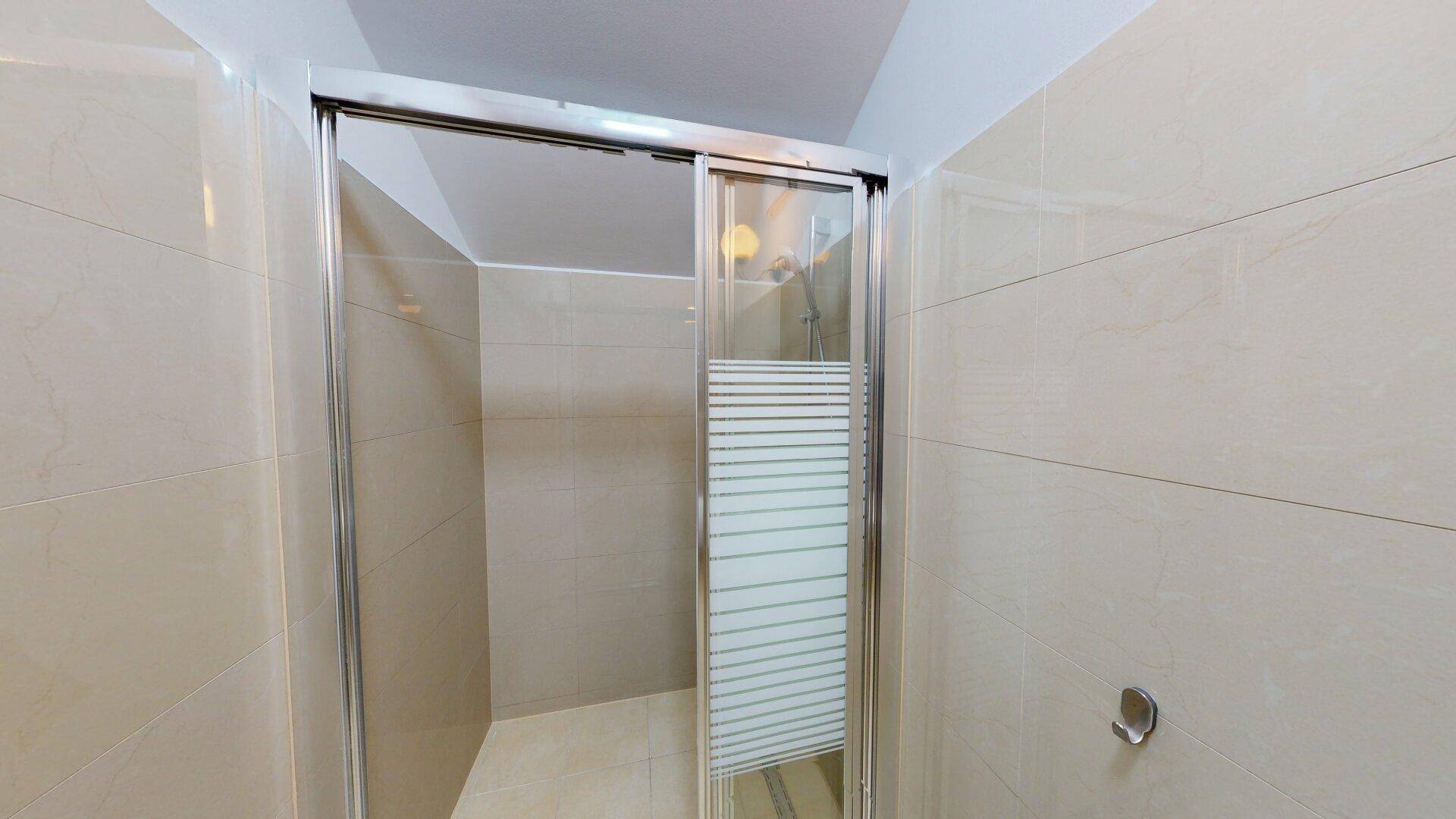 Moderne Duschkabine mit Glaswänden und hellen Fliesen im Badezimmer.