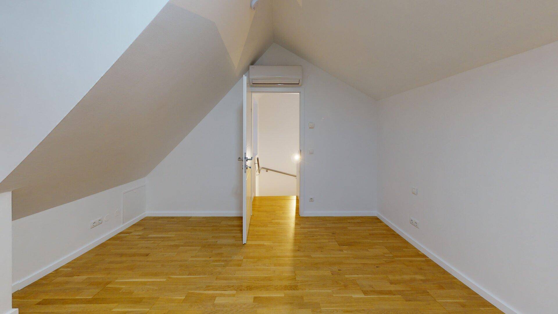 Ruhiges Schlafzimmer im Dachgeschoss mit Holzboden, Dachschrägen und Klimaanlage, mit Flurzugang.
