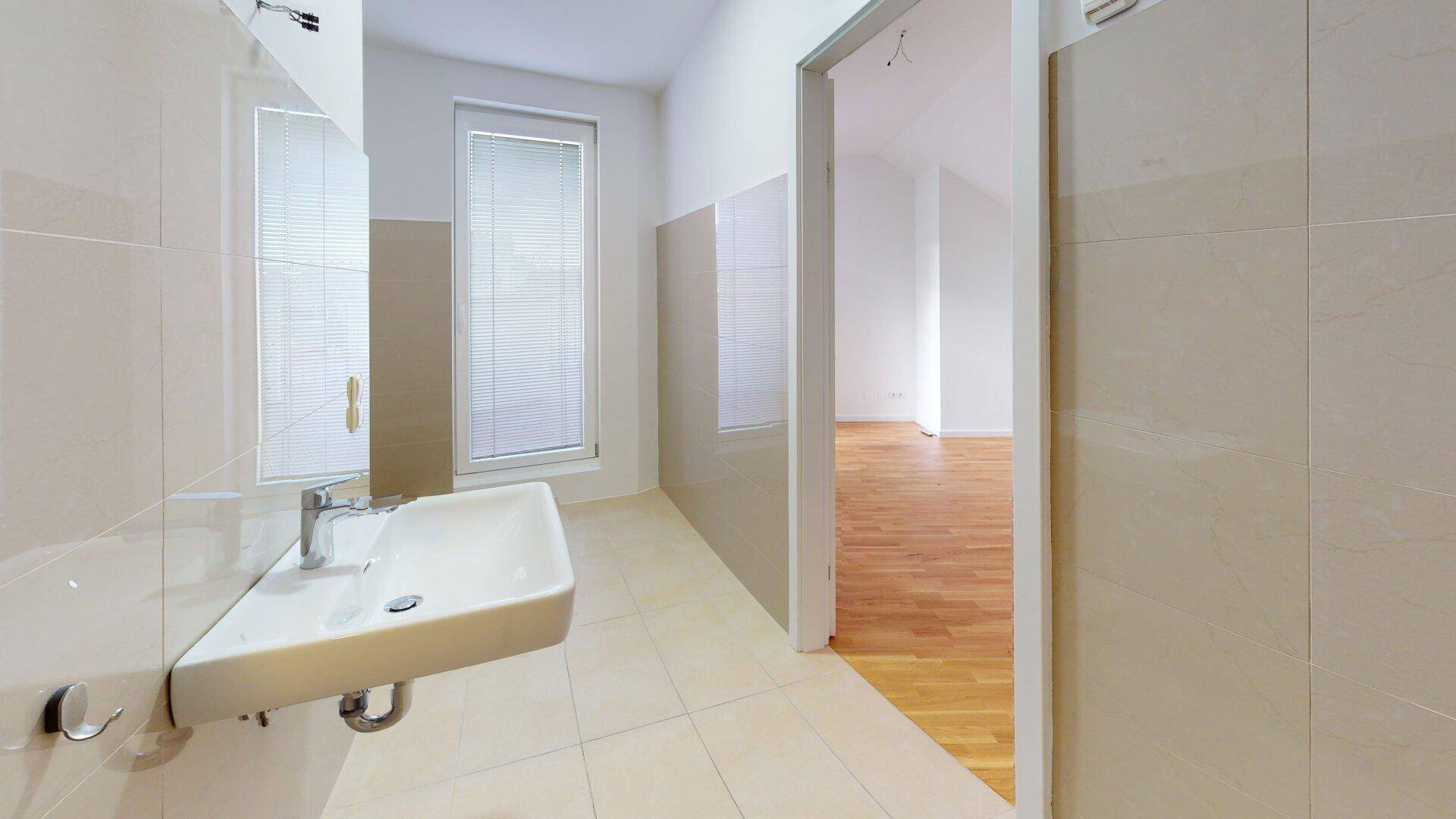 Helles Badezimmer mit Einzelwaschbecken, Fenster und beigefarbenen Fliesen an Wänden und Boden.