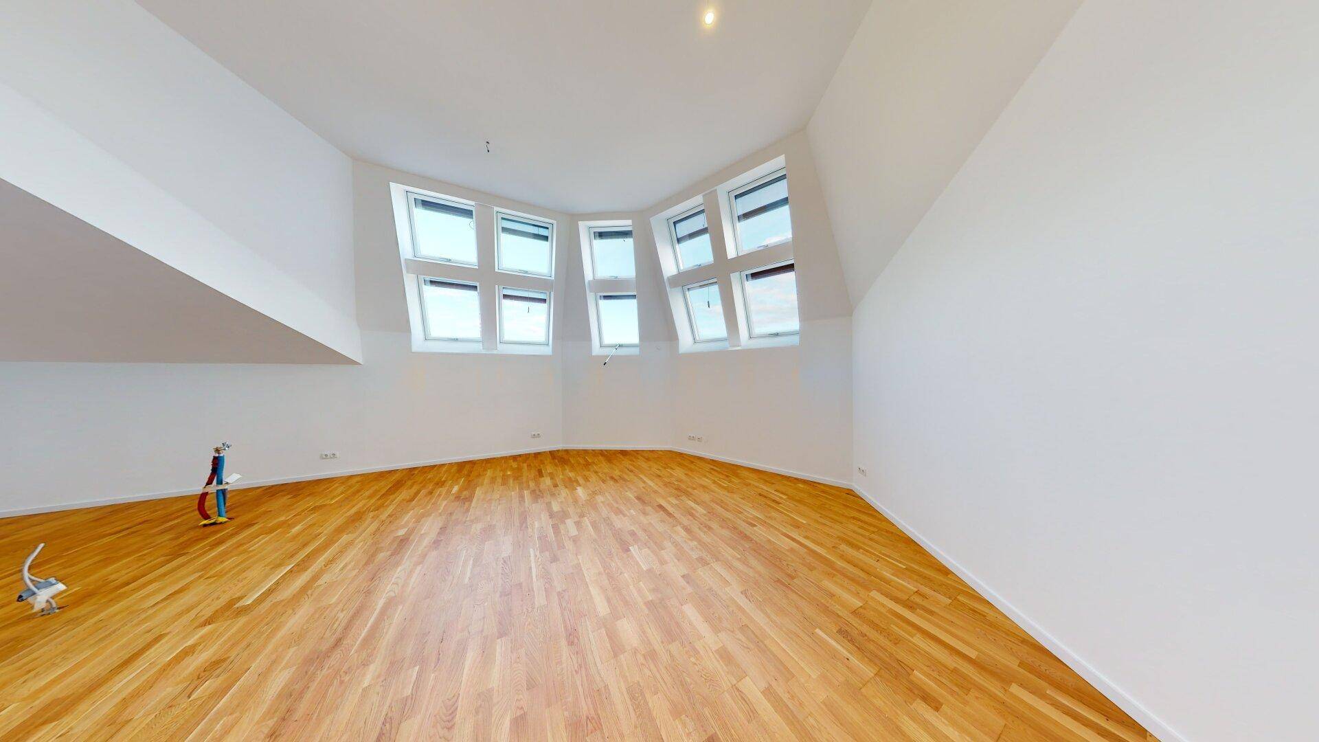 Geräumiger Dachgeschossraum mit Holzboden und vielen Dachfenstern, ideal als Wohnbereich nutzbar.