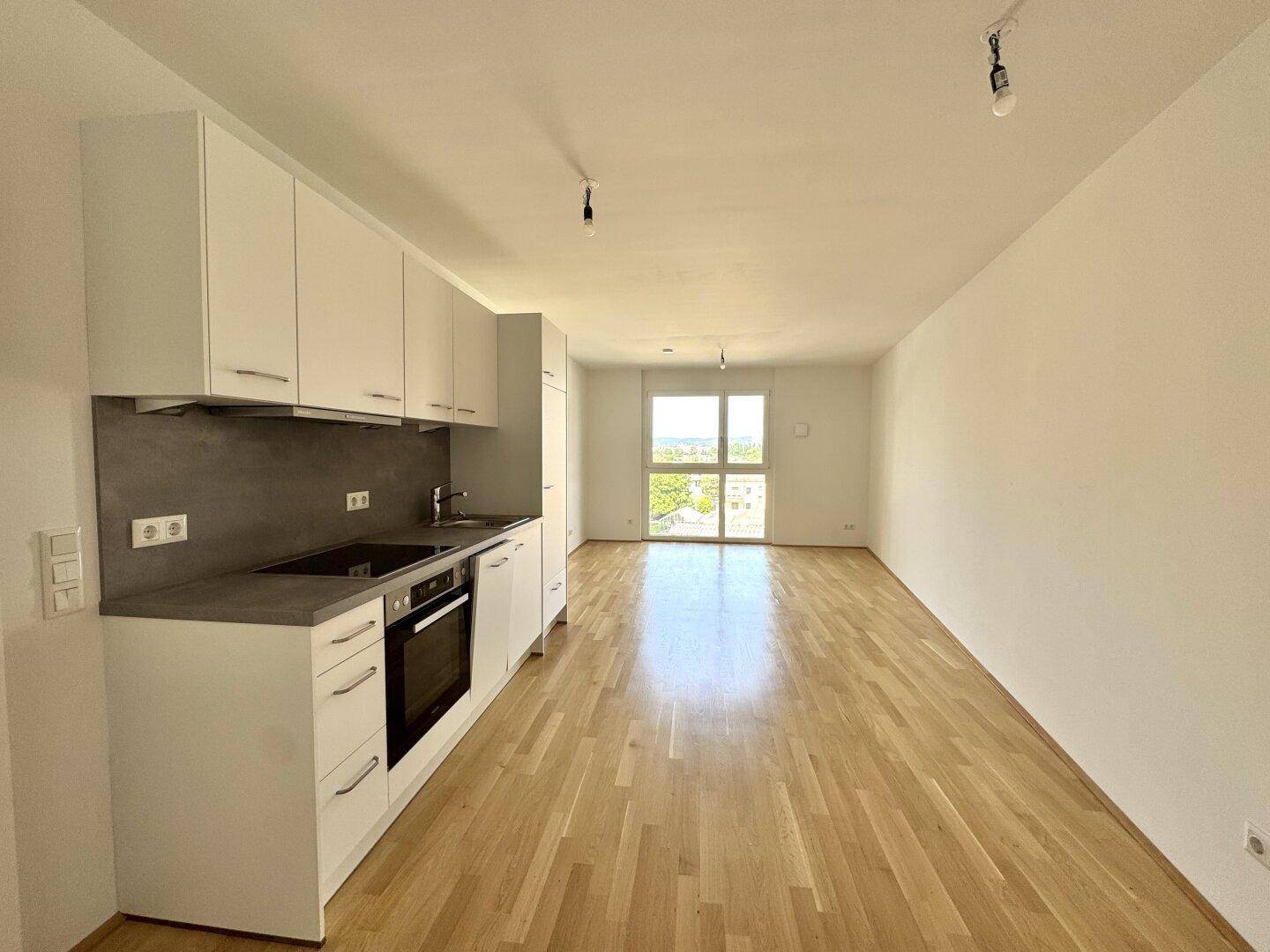 Moderne Küchenzeile in einem hellen Wohnbereich mit Zugang zu einem Balkon.