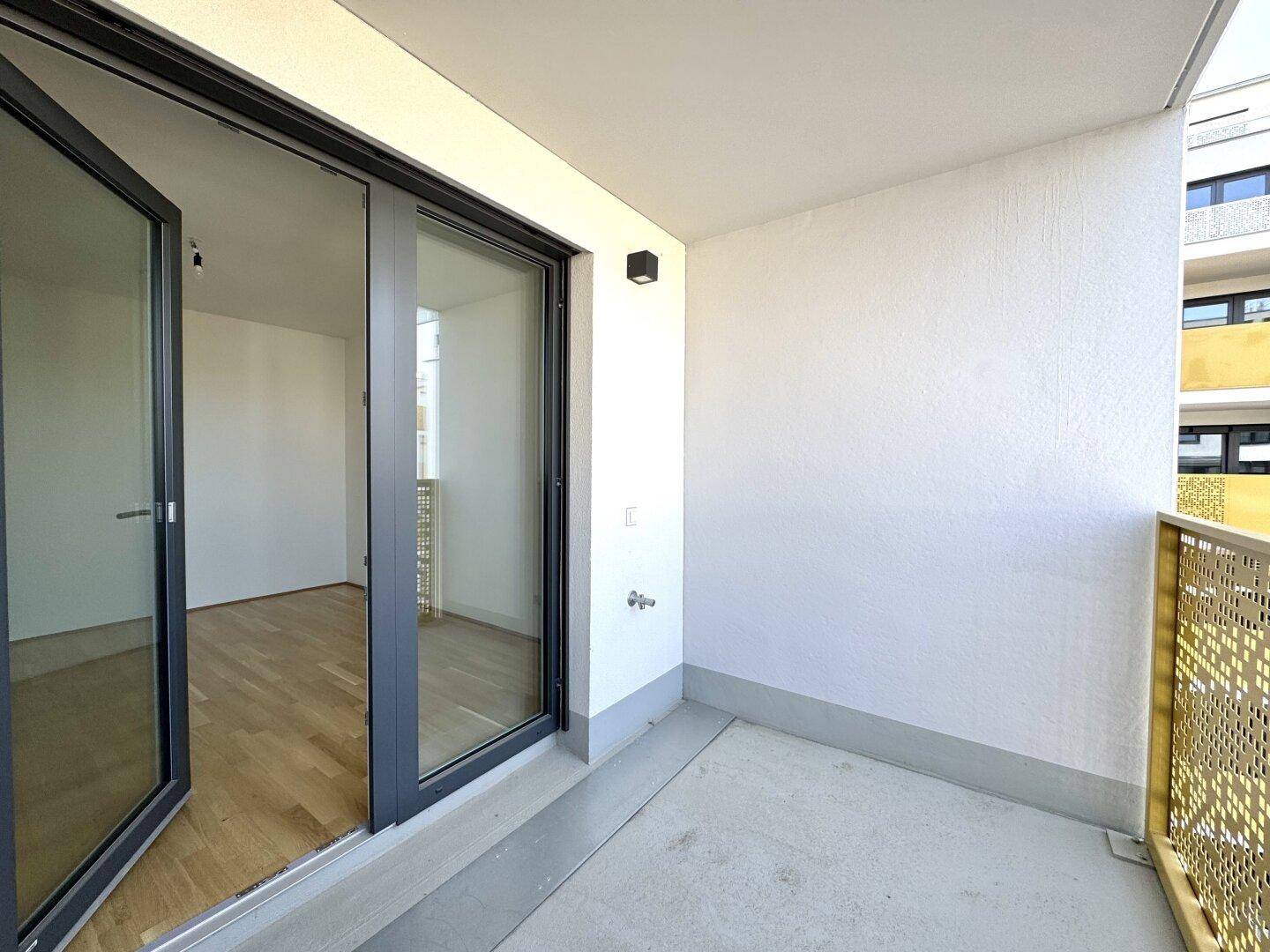 Kleiner Balkon mit modernem Geländer und Blick in den hellen Innenraum.