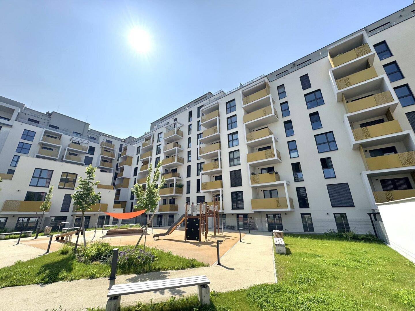 Moderne Wohnanlage mit zahlreichen Balkonen, einem Spielplatz und gepflegten Grünflächen.