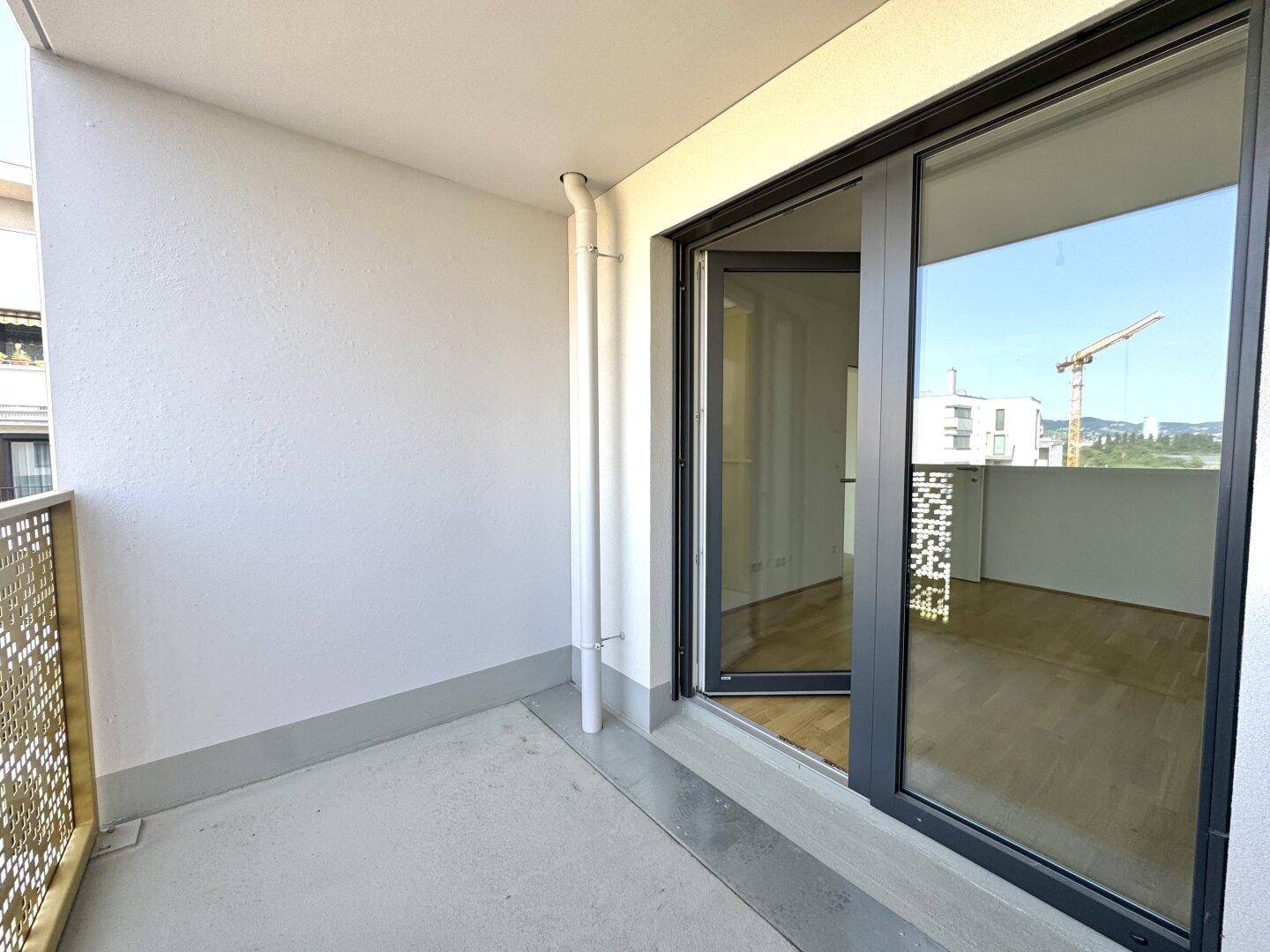 Kleiner, unmöblierter Balkon mit Betonboden und dekorativem Metallgeländer, zugänglich vom Innenraum.