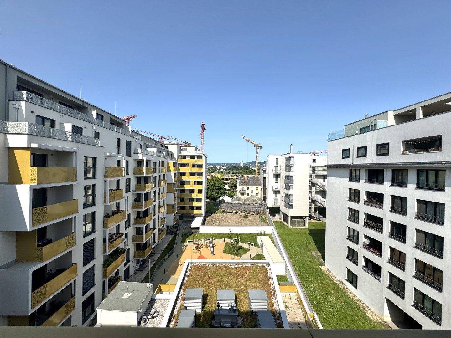 Weitläufiger Blick auf den Innenhof mit Spielplatz, umgeben von modernen Wohngebäuden.