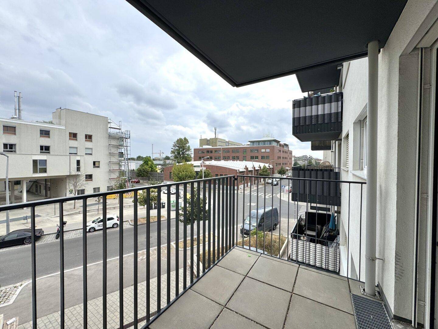 Aussicht vom Balkon auf die Straße und angrenzende moderne Gebäude in urbaner Umgebung.