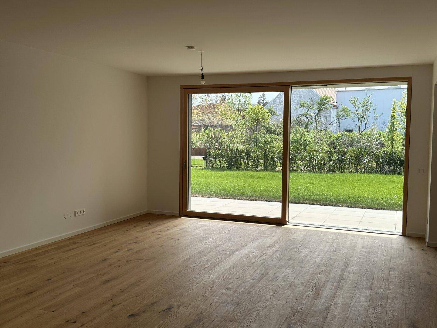 Helles Wohnzimmer mit Holzboden und großer Schiebetür zum Garten und zur Terrasse.