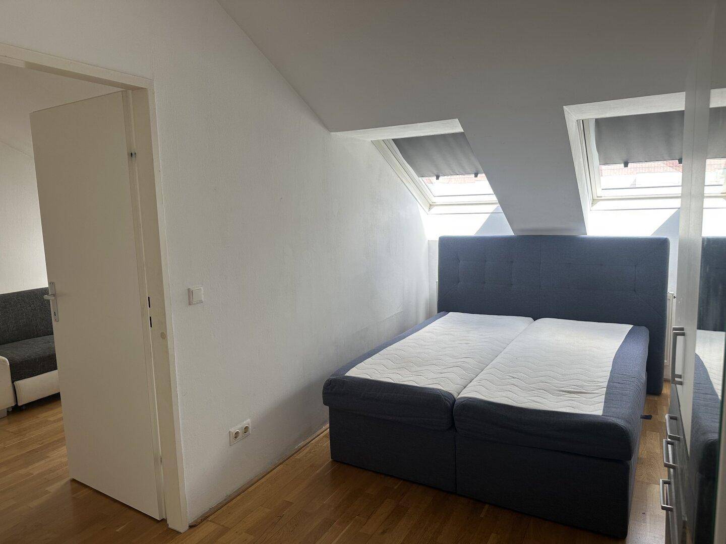 Schlafzimmer im Dachgeschoss mit Doppelbett, Holzboden und Dachfenstern für viel Licht.