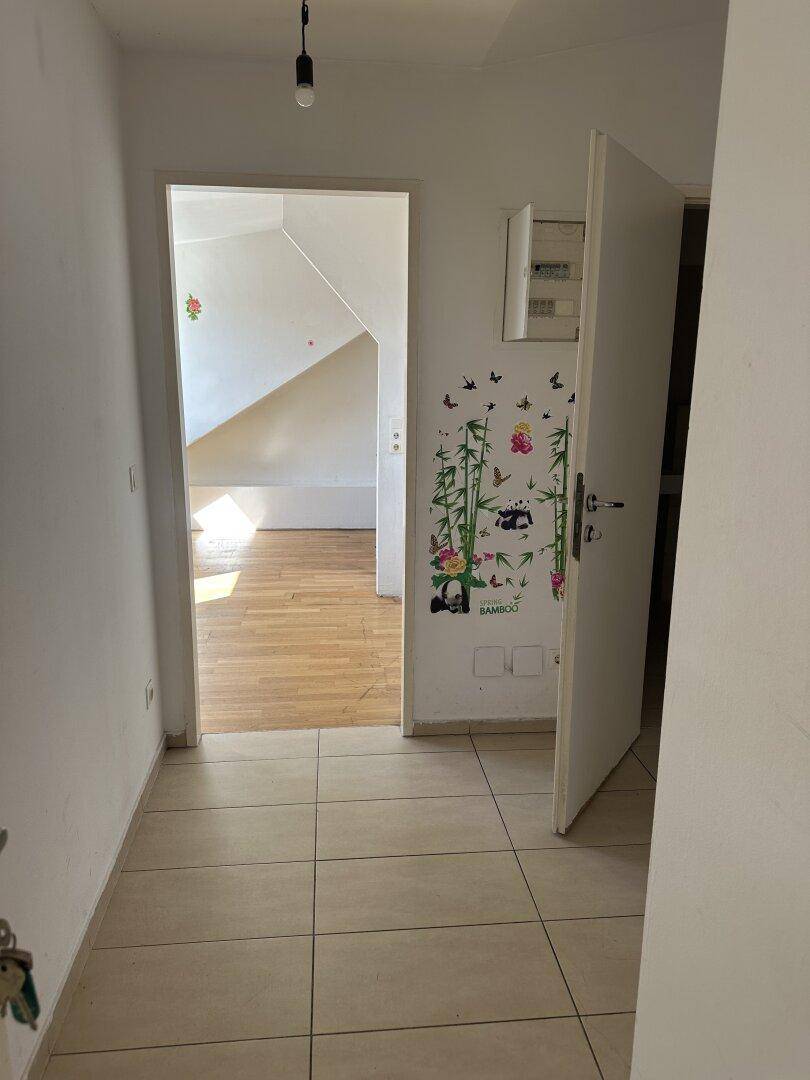 Eingangsbereich mit Fliesenboden, dekorativem Wandsticker und Blick in den Wohnbereich.