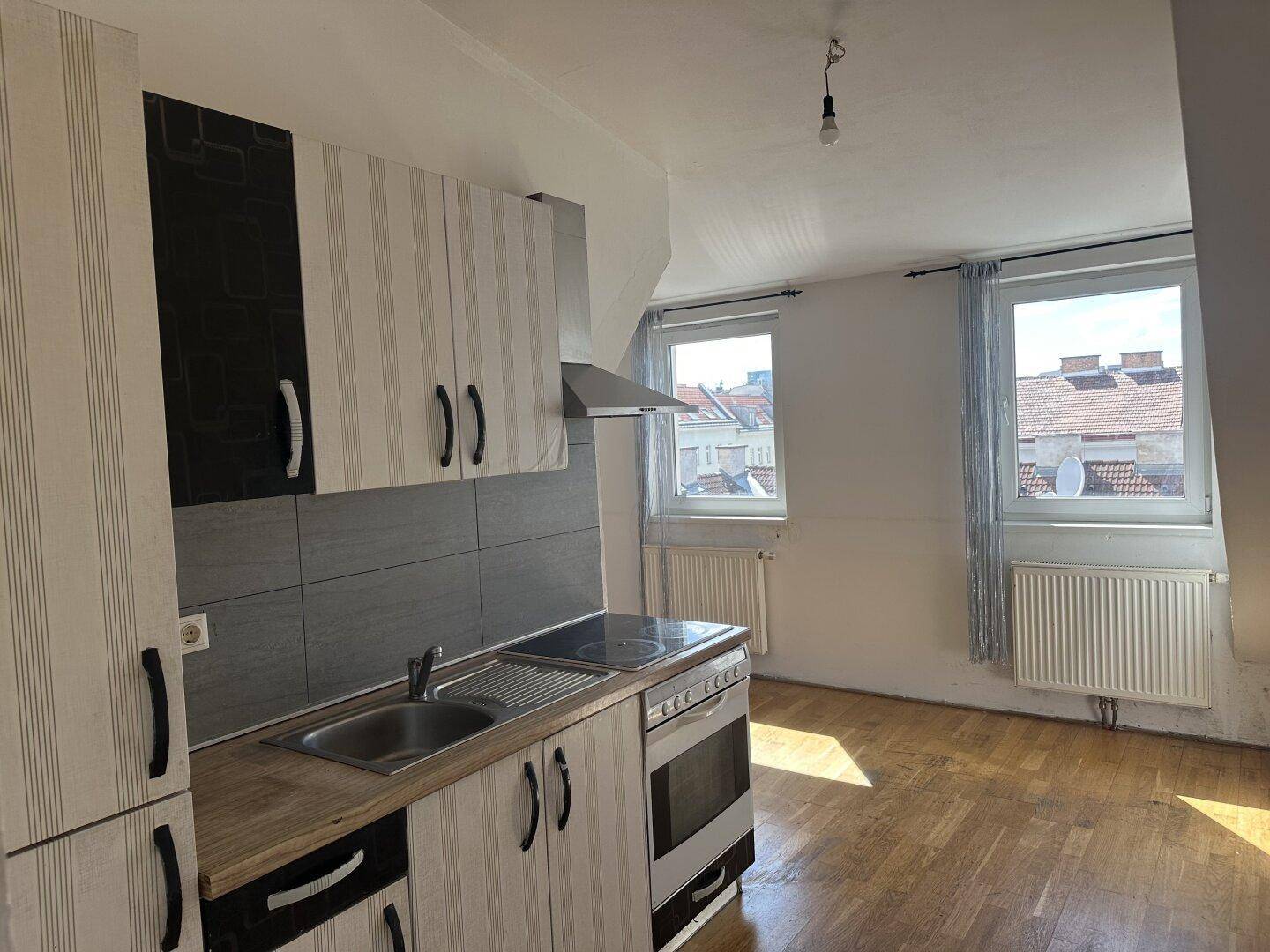 Helle Dachgeschossküche mit Holztheke, gestreiften Schränken und Blick über die Dächer.