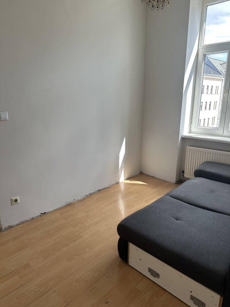 Heller Raum mit Holzfußboden und großem Fenster, ideal als Wohn- oder Schlafzimmer.