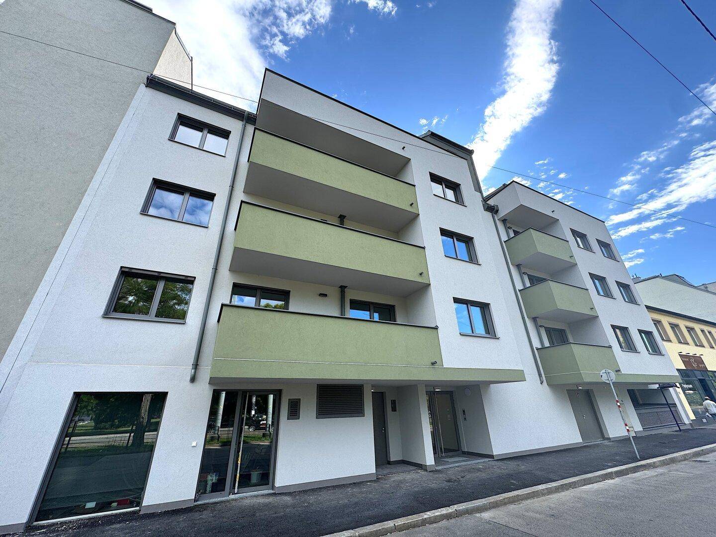 Neubau-Wohngebäude mit moderner Architektur, hellen Fassaden und mehreren Balkonen.