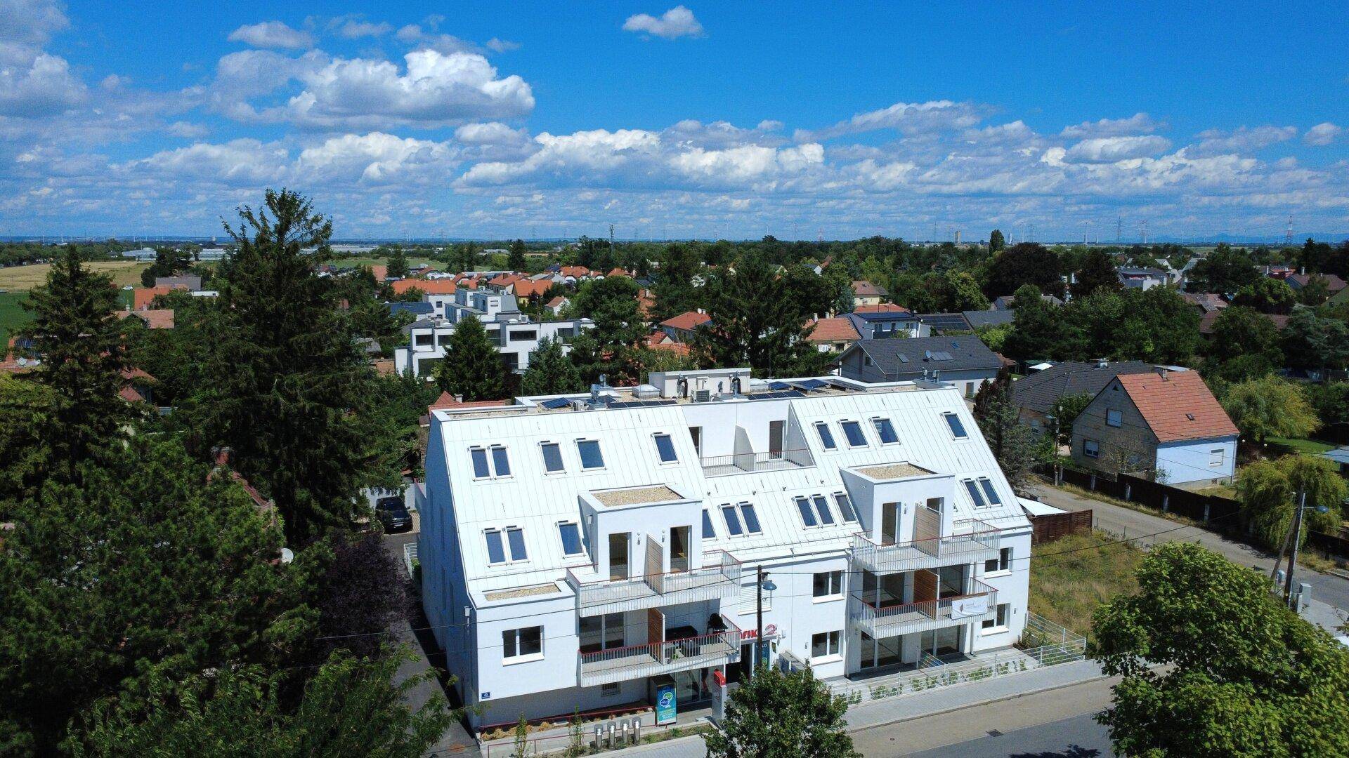Panoramablick aus der Luft auf das moderne Wohnhaus und die umliegende grüne Landschaft.