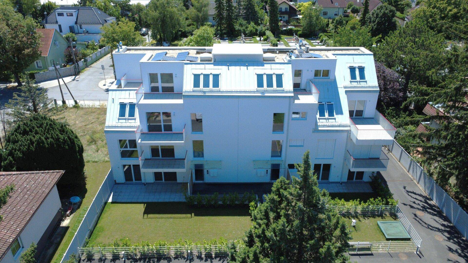 Neubau-Wohnhaus mit klarer Architektur, mehreren Balkonen und gepflegter Grünfläche im Außenbereich.