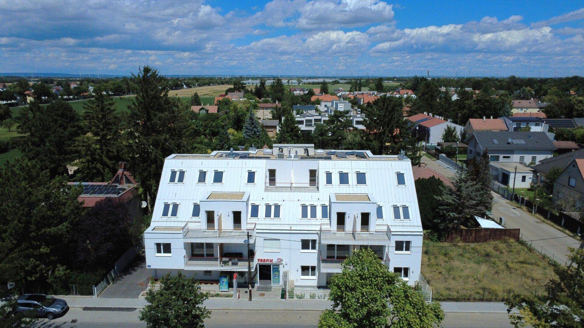 Modernes Wohngebäude in ländlicher Umgebung mit weitem Blick über Felder und angrenzende Häuser.